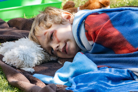A sulking boy - Neurodivergent child, lies on a blanket in the garden