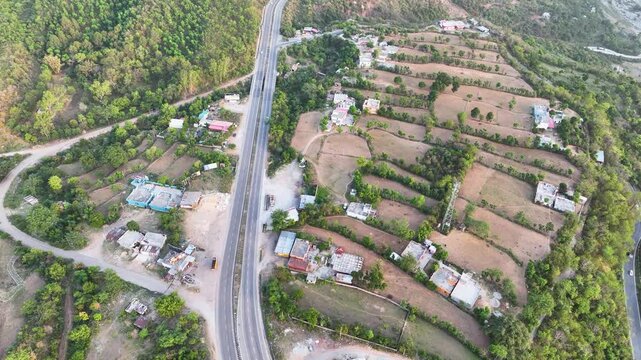 Infrastructure meets agriculture: Highway through rural Jammu. Drone shot of rural Indian highway and stepped agricultural fields.