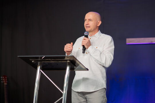 Christian pastor speaking at transparent podium during church worship cross background with service