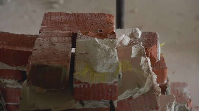 Close up view of broken red bricks, white plaster, metal pipe. Shallow depth of field focuses on texture of rubble. Muted, earthy colors create industrial grunge mood. For renovation concepts