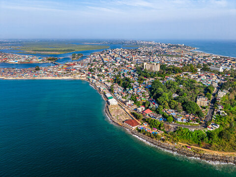 Aerial view of the dense urban landscape and lush green hills along the Atlantic coastline in Monrovia, Liberia.
