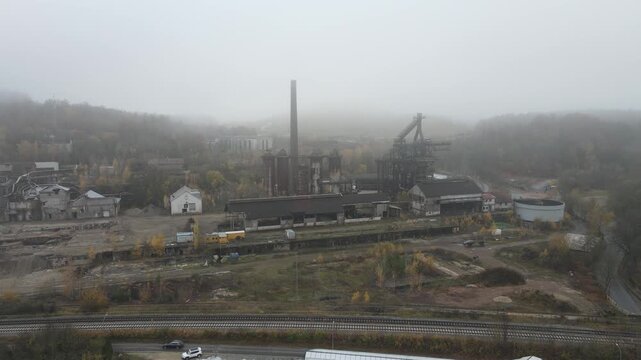Drone moves slightly forward and left to right toward the rusted former steelworks in misty industrial weather