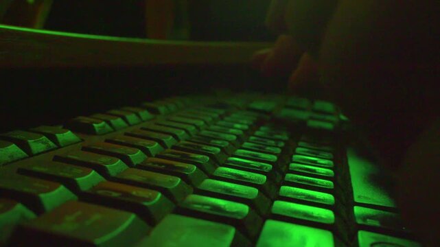  Macro shot of programmer hands coding on laptop keyboard in dark room, slow motion.