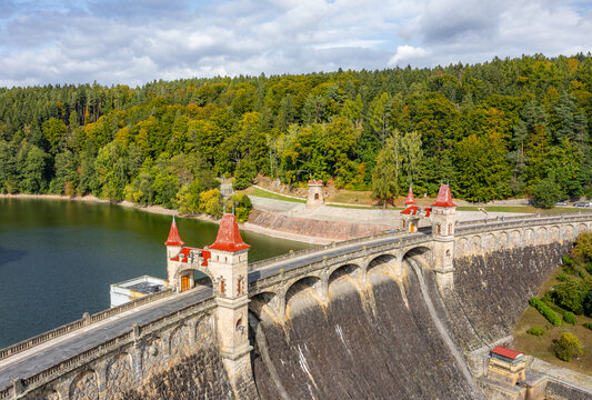 Aerial view of the historic Royal Forest Dam featuring red-roofed towers and a reservoir surrounded by lush autumn forest in Bila Tremesna, Hradec Kralove Region, Czechia.