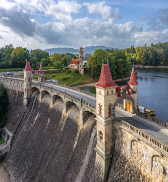 Aerial view of the historic Royal Forest Dam with its fairy-tale stone towers and red roofs surrounded by lush green forests in Bila Tremesna, Hradec Kralove Region, Czechia.