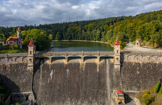 Aerial view of the Royal Forest Dam featuring historic stone architecture and red-roofed towers surrounded by lush green forest in Bila Tremesna, Hradec Kralove Region, Czechia.