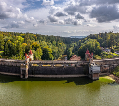 Aerial view of the Royal Forest Dam featuring its distinctive fairy-tale towers with red roofs surrounded by lush green forests under a cloudy sky in Bila Tremesna, Hradec Kralove Region, Czechia.