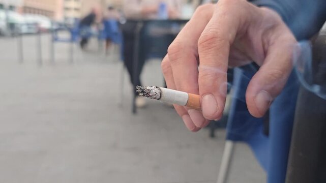 Close up of a man's hand holding a lit cigarette, symbolizing the World No Tobacco Day concept