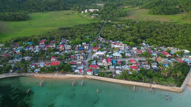 Aerial view of Magnesia Del Norte in Virac, Catanduanes with shoreline homes, fishing bangka boats, reef water, and tropical hills