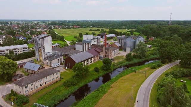 Industrial wheat refinery beside Iecava river surrounded by green farmland view