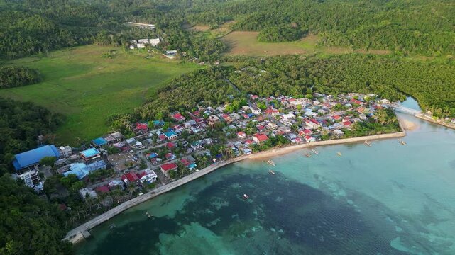 Scenic aerial pullback of rural barangay village along lush tropical island coastline - Magnesia Del Norte, Virac, Catanduanes, Philippines