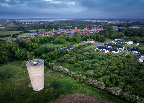 Aerial view of the historic St. Ita's Hospital complex and a tall concrete water tower surrounded by lush green trees and fields Portrane, County Dublin, Ireland.