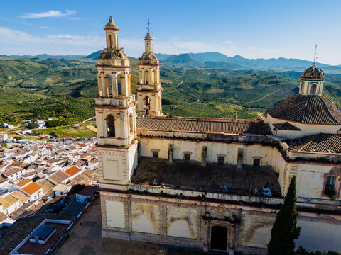 Aerial view of the Parish of Our Lady of the Incarnation with its twin bell towers and dome overlooking the white houses and green hills of Olvera, Andalusia, Spain.