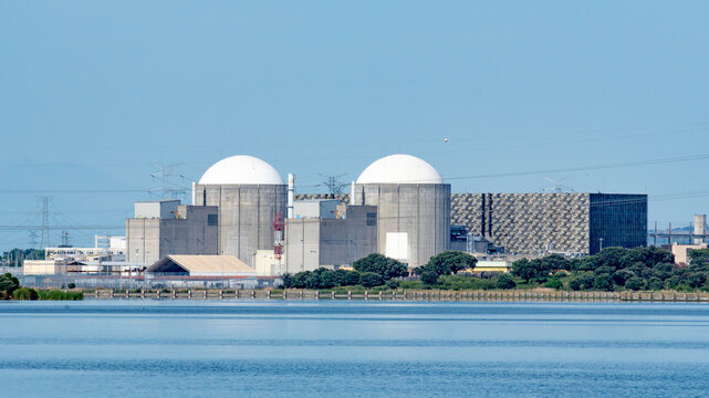 Almaraz, Caceres, Spain - 2026 April 19: Large industrial facility of Almaraz nuclear power plant  situated by a lake, featuring two prominent reactor buildings and transmission towers