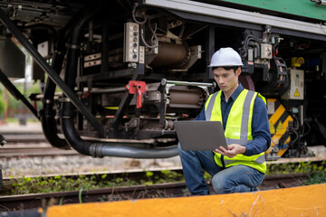 Fototapeta premium Engineer inspecting and monitoring railway machinery with laptop outdoors