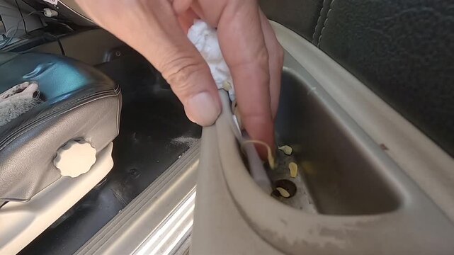 Removing discarded tissues and leftover food scraps from the side pocket compartment of a car door.