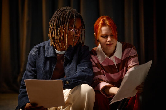 Biracial students reviewing papers together, discussing school project and studying collaboratively. Education teamwork concept for academic marketing, tutoring services, student campaigns
