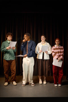 Vertical shot of diverse students rehearsing stage presentation, reading scripts and speaking into microphone. Education marketing, youth workshop, public speaking campaign use
