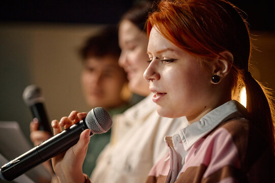 Young adult student speaking into microphone during student panel discussion, presenting ideas in educational setting

