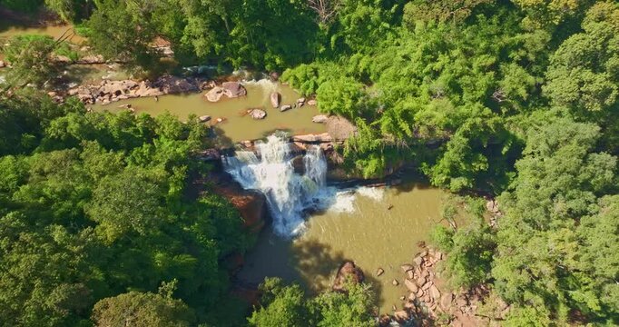 Aerial view of Tat Huang Waterfall flowing through lush green forest at Phu Suan Sai National Park in Loei Province, Thailand. This international waterfall forms a natural border Thailand and Laos