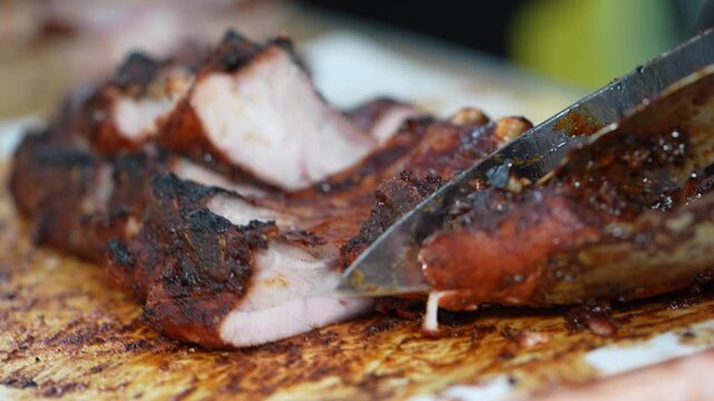A chef grills ribs on a large BBQ grill outdoors.
