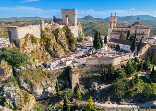 Aerial view of the historic Castillo de Olvera and the Parroquia de Nuestra Senora de la Encarnacion on a rocky outcrop under a clear blue sky in Olvera, Andalusia, Spain.