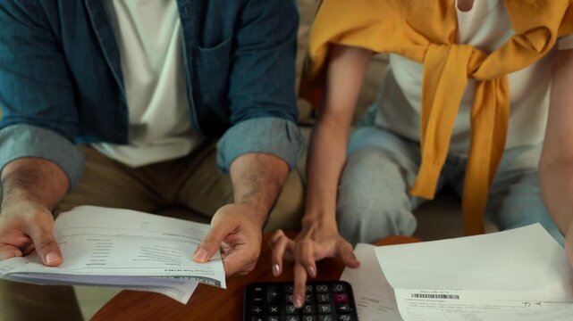 Close-up Stressed married couple calculating household expenses and debt payments with bills at home. Financial crisis, economic problems, inflation and family budget planning concept.
