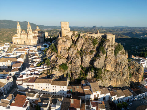 Aerial view of the Castillo de Olvera and the church of Nuestra Senora de la Encarnacion on a rocky hilltop surrounded by white houses in Olvera, Andalusia, Spain.