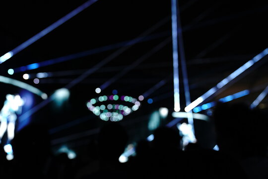 Abstract colorful concert bokeh background with blurred stage lights and glowing pink light stick silhouette, creating an energetic nightlife and live music atmosphere with soft defocused illumination