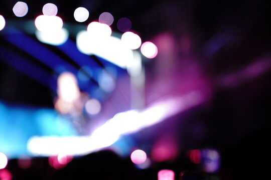 Abstract colorful concert bokeh background with blurred stage lights and glowing pink light stick silhouette, creating an energetic nightlife and live music atmosphere with soft defocused illumination
