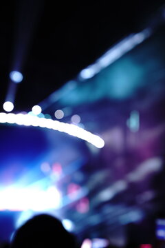 Abstract colorful concert bokeh background with blurred stage lights and glowing pink light stick silhouette, creating an energetic nightlife and live music atmosphere with soft defocused illumination