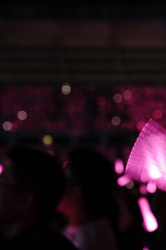 Abstract colorful concert bokeh background with blurred stage lights and glowing pink light stick silhouette, creating an energetic nightlife and live music atmosphere with soft defocused illumination