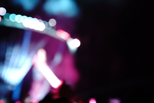 Abstract colorful concert bokeh background with blurred stage lights and glowing pink light stick silhouette, creating an energetic nightlife and live music atmosphere with soft defocused illumination