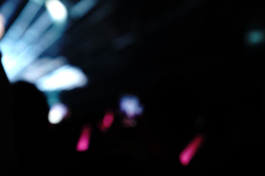 Abstract colorful concert bokeh background with blurred stage lights and glowing pink light stick silhouette, creating an energetic nightlife and live music atmosphere with soft defocused illumination