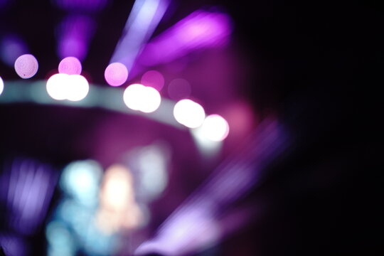 Abstract colorful concert bokeh background with blurred stage lights and glowing pink light stick silhouette, creating an energetic nightlife and live music atmosphere with soft defocused illumination