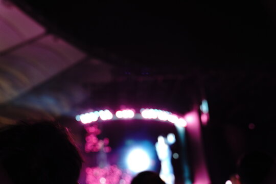 Abstract colorful concert bokeh background with blurred stage lights and glowing pink light stick silhouette, creating an energetic nightlife and live music atmosphere with soft defocused illumination