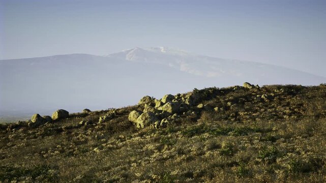 Open ridge with gentle slope and clear teal sky, broad exposure and scattered rocks suggest solar feasibility potential, engineering planning and sustainable