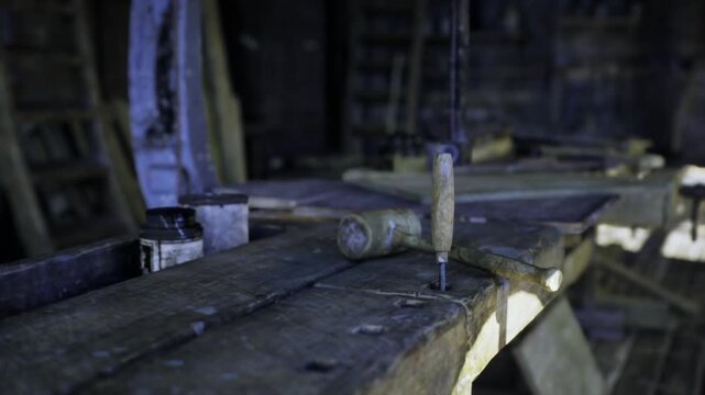 Close view of vise clamp secured to aged workbench, screw threads and metal texture in focus. Scene reads like restorers station, with rusted hardware,