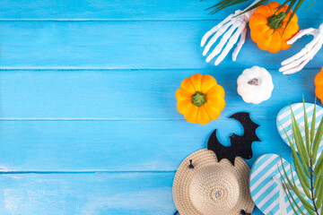 Summerween holiday background. Bright festive background for summer Halloween holiday in style of Halloween with summer decorations, pumpkins, ghost, bat, summer vacation accessories, tropical leaves © ricka_kinamoto
