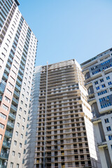 Fototapeta premium Urban high-rise buildings with a central unfinished tower in bright daylight