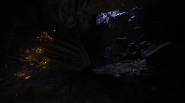 Dim candle clusters inside cavern adventurer finding moonlit exit wet stone reflecting pale blue skylight scattered embers echoing silence moody frame
