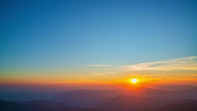 Gentle rays rise above the distant ridges, illuminating the wilderness with a warm morning shimmer. This time lapse showcases the peaceful beauty of a mountain sunrise spreading across the horizon.