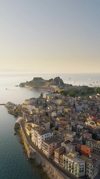Vertical panoramic drone shot of Corfu Old Town during sunrise with the promenade and Old Fortress visible