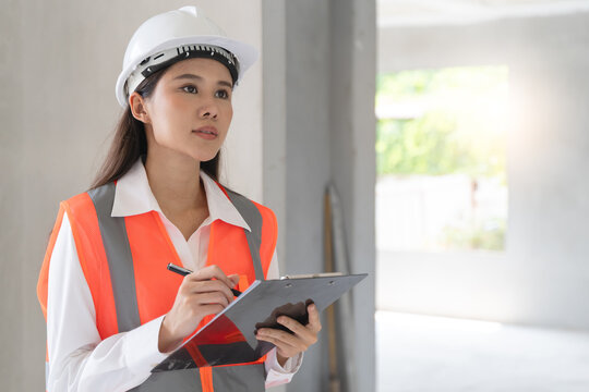 Asian inspector checking structure of new property and taking note in the clipboard for review and fix the house before sell to client