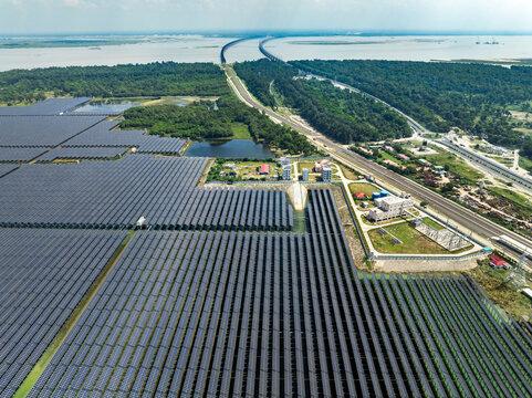 Aerial view of a vast solar panel farm situated near the Jamuna Bridge and lush green forests along the riverbank in Sirajganj, Rajshahi Division, Bangladesh.