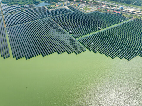 Aerial view of a massive floating solar farm with rows of photovoltaic panels on greenish water near industrial infrastructure in Sirajganj, Rajshahi Division, Bangladesh.