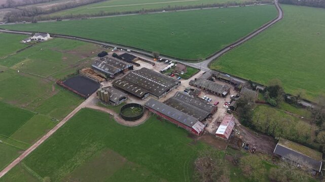Aerial video showing farmland fields beside a tree covered landscape in sunlight.