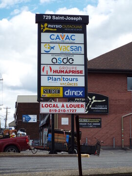 Gatineau, Quebec, Canada &ndash; May 1, 2026: A tall tenant directory pylon sign at '729 Saint-Joseph" lists multiple professional businesses above a "Local &agrave; louer" space available sign on boulevard St-Jos