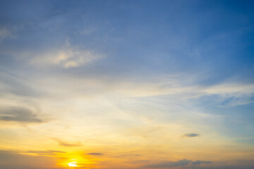 Fototapeta premium A breathtaking sunset sky with soft, wispy clouds and a vibrant golden glow casting a warm light over the horizon.