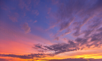 Fototapeta premium A breathtaking, vibrant sunset sky filled with dramatic, textured clouds painted in brilliant shades of fiery orange, deep magenta, and soothing twilight purple, capturing the serene beauty.